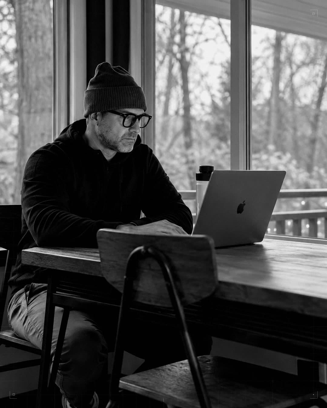 Jason Murphy working at a table by a window, laptop open.
