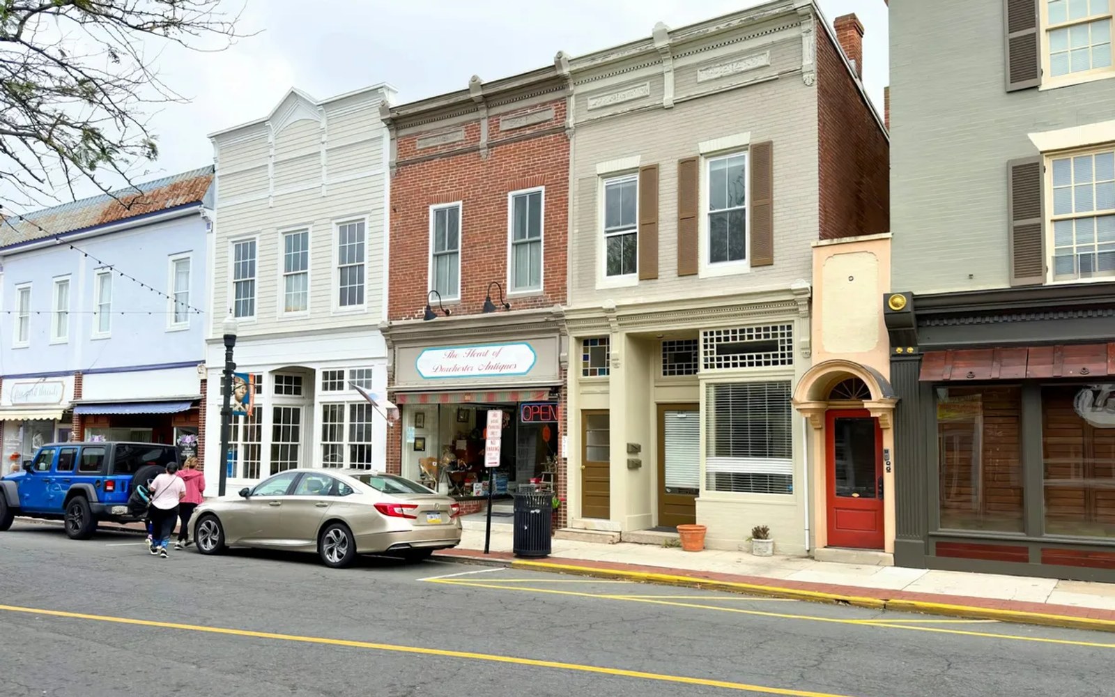 A row of small-town storefronts on a main street, one with its OPEN sign lit — the kind of local business Google and Maps decide for.