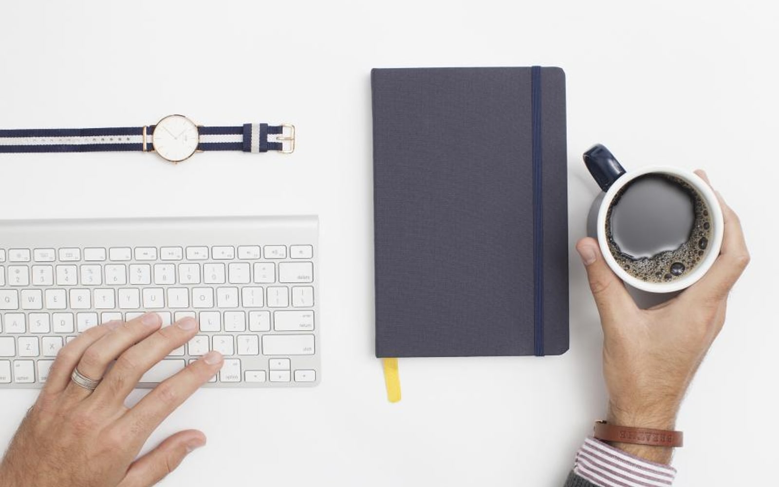 Hands at a keyboard beside a notebook and a coffee, seen from above — the places a business’s facts live.